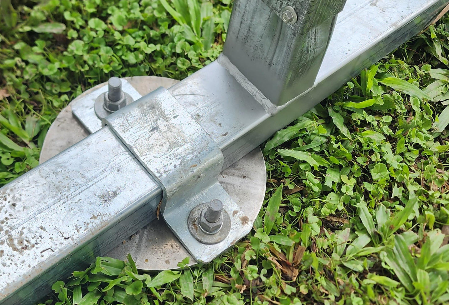 Galvanized metal ground anchor with bolts and round base plate